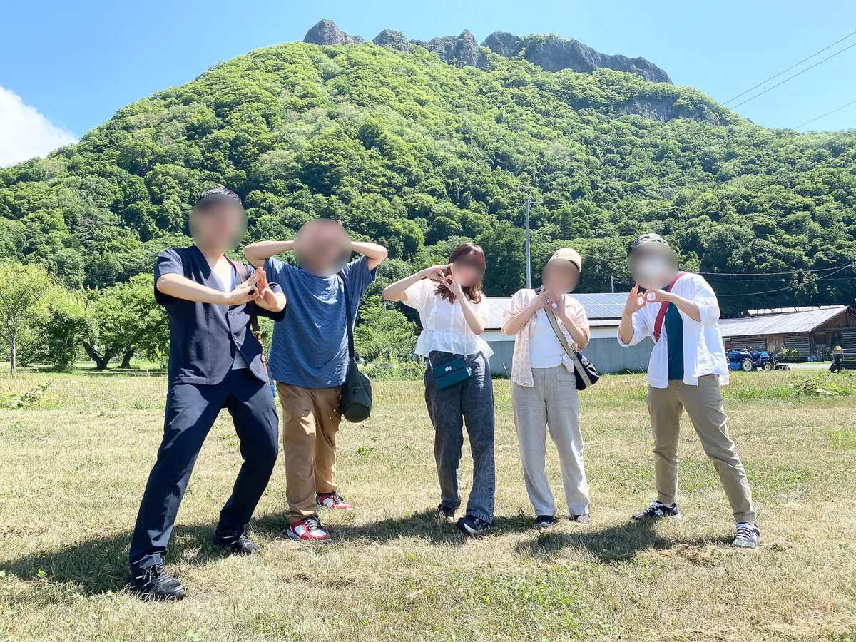 山を背景に果物狩りの帰りに記念撮影する様子